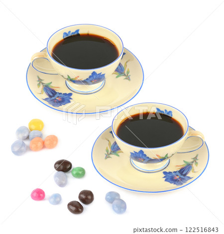 Coffee in vintage porcelain cup and dragee candies isolated on white background. Free space for text. Coffee in vintage porcelain cup and dragee candies isolated on white background. Free space for text. 122516843