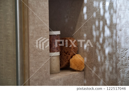 Body care products (scrubs and a natural washcloth) on the shower shelf. 122517046