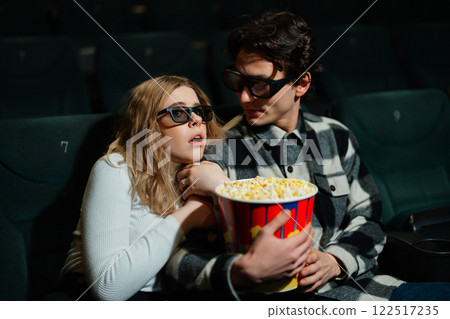 Couple enjoying a thrilling movie experience with popcorn in a cinema Couple enjoying a thrilling movie experience with popcorn in a cinema 122517235