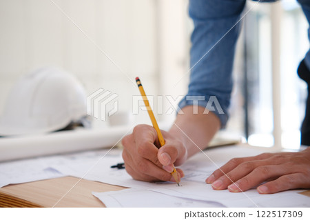 Young architect sketching house plans on a work desk in a modern office Young architect sketching house plans on a work desk in a modern office 122517309