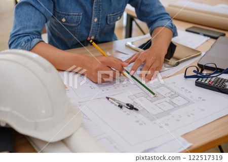 Young architect sketching house plans on a work desk in a modern office 122517319