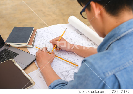 Young architect sketching house plans on a work desk in a modern office 122517322