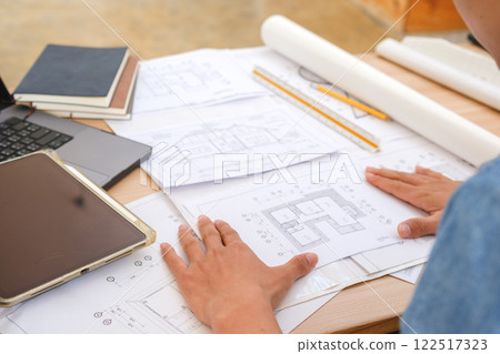 Young architect sketching house plans on a work desk in a modern office Young architect sketching house plans on a work desk in a modern office 122517323