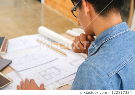 Young architect sketching house plans on a work desk in a modern office 122517324