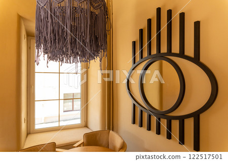 Macrame lampshade with fringes, suspended in front of a warm, background. Macrame lampshade with fringes, suspended in front of a warm, background. 122517501