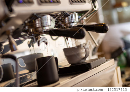 Closeup of pump driven espresso machine and portafilter brewing by forcing pressurized water through puck. Closeup of pump driven espresso machine and portafilter brewing by forcing pressurized water through puck. 122517513