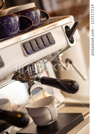 Closeup of pump driven espresso machine and portafilter brewing by forcing pressurized water through puck. Closeup of pump driven espresso machine and portafilter brewing by forcing pressurized water through puck. 122517514