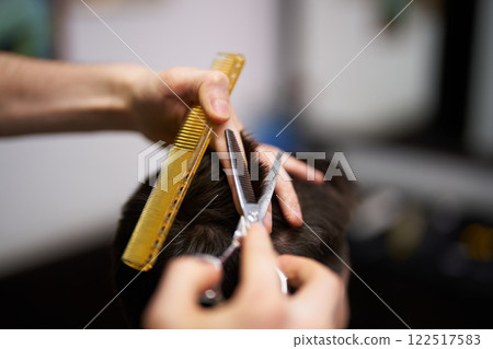 Haircut in progress at a barbershop with professional tools involved Haircut in progress at a barbershop with professional tools involved 122517583
