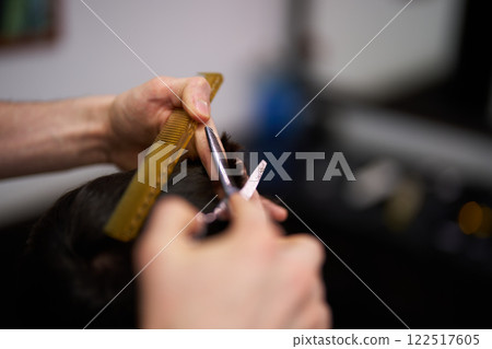 Skilled hands cutting hair in a salon setting with bright lighting Skilled hands cutting hair in a salon setting with bright lighting 122517605
