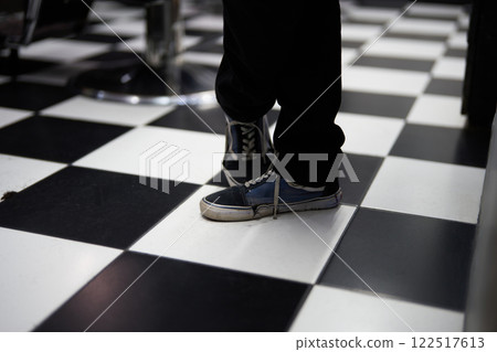 Person standing in sneakers on a black and white checkered floor 122517613