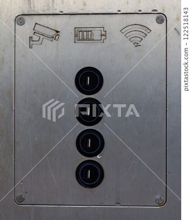 Metal panel featuring four usb charging ports, accompanied by engraved icons representing surveillance, battery status, and wi-fi connectivity. Ideal for public spaces and tech environments. Metal panel featuring four usb charging ports, accompanied by engraved icons representing surveillance, battery status, and wi-fi connectivity. Ideal for public spaces and tech environments. 122518143