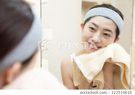 A woman who wipes her face with a towel after washing her face A woman who wipes her face with a towel after washing her face 122518618
