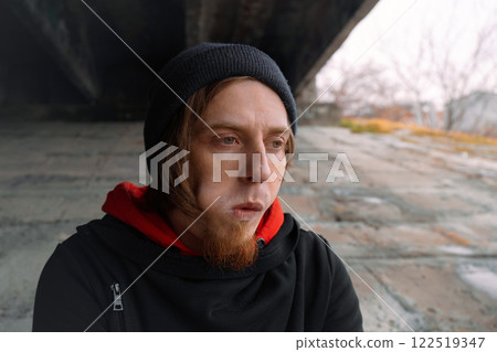 Contemplative person in an urban setting reflecting on life beneath a bridge during a chilly afternoon in early winter 122519347