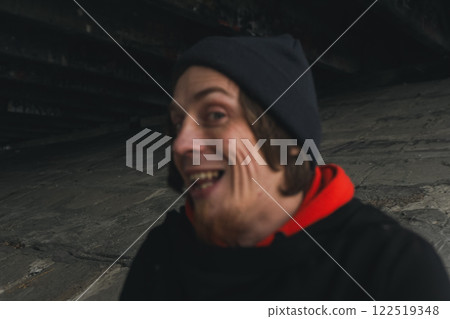 A joyful moment captured under the bridge with a spirited individual wearing a red hoodie and black beanie at dusk 122519348