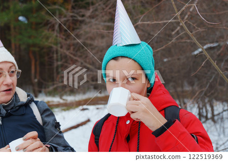 Friends celebrate winter with treats and warm drinks in a snowy forest during a festive outing 122519369