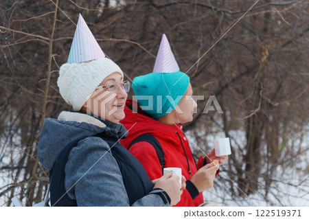 Enjoying warm drinks and laughter in the winter woods with festive hats and friends Enjoying warm drinks and laughter in the winter woods with festive hats and friends 122519371