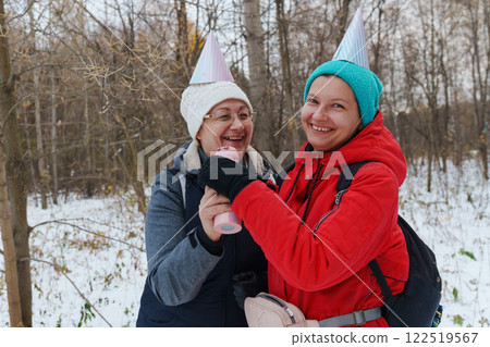 Winter adventure shared by two friends celebrating joyfully in a snowy forest with festive hats 122519567