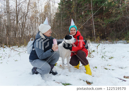 Two friends wearing colorful winter attire and party hats joyfully play in the snow 122519570