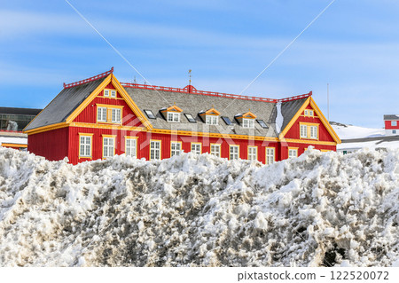 Old red Danish colonial building with snow heap in the foreground, Historical center of Nuuk, Greenland 122520072