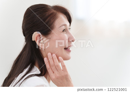 Senior woman wearing a hearing aid 122521001