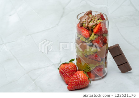 Viral Dubai chocolate strawberry cup with kunafa, pistachio paste, tahini, milk chocolate and fresh strawberries. Decorated with strawberries and chocolate bar piece. Copy space for text. Viral Dubai chocolate strawberry cup with kunafa, pistachio paste, tahini, milk chocolate and fresh strawberries. Decorated with strawberries and chocolate bar piece. Copy space for text. 122521176