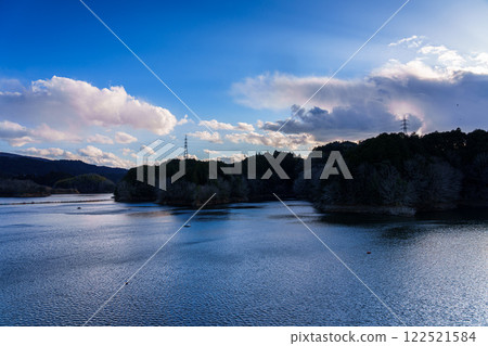 Nara City's Suijin Nunome Dam in the Yamato Plateau in the eastern part of Nara City - Midwinter scenery - clouds rising from the mountainside and the lake surface shining blue Nara City's Suijin Nunome Dam in the Yamato Plateau in the eastern part of Nara City - Midwinter scenery - clouds rising from the mountainside and the lake surface shining blue 122521584