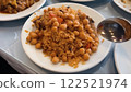 Savory Rice Pilaf with Chickpeas and Vegetables Being Served with a Spoon on a White Ceramic Plate 122521974