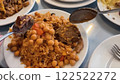 Serving Spoons with Meat and Rice Pilaf with Chickpeas, Carrots, and Raisins on White Ceramic Plates 122522272
