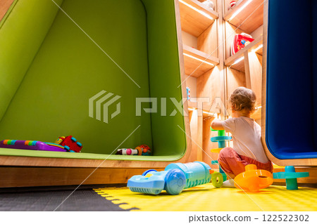 Little child enjoying creative playtime with a toy vacuum cleaner in a bright and interactive playroom 122522302