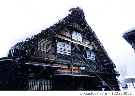Snow falling on a Gassho-style house 122523091
