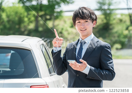 一名年輕的亞洲男子，在汽車經銷店擔任評估師/推銷員，正在評估汽車 122523858