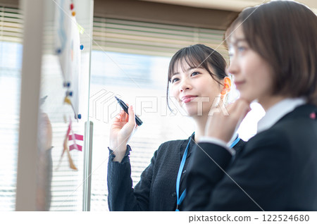 Two young businesswomen analyzing data using a whiteboard 122524680