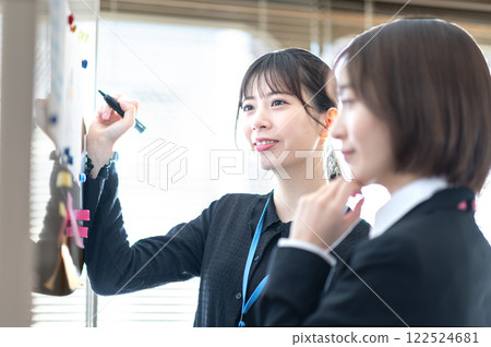 Two young businesswomen analyzing data using a whiteboard 122524681