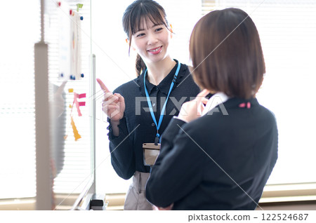 兩位年輕的女商人使用白板分析數據 兩位年輕的女商人使用白板分析數據 122524687