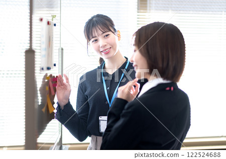 兩位年輕的女商人使用白板分析數據 122524688