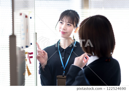 Two young businesswomen analyzing data using a whiteboard Two young businesswomen analyzing data using a whiteboard 122524690