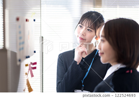 Two young businesswomen analyzing data using a whiteboard 122524693