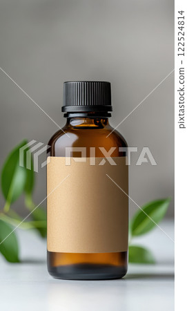 Minimalist brown bottle with blank label and green leaves nearby 122524814