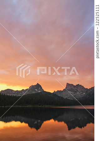 Golden sunset in mountain lake. Two peaks reflected in water Golden sunset in mountain lake. Two peaks reflected in water 122525111