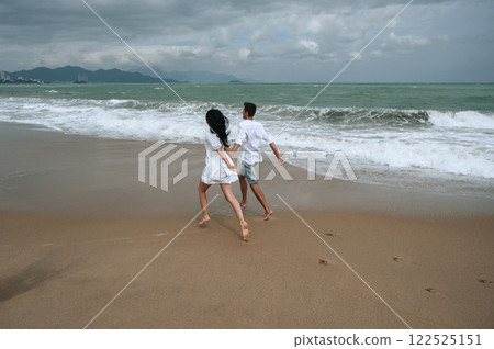 back of couple in love runs along beach by the sea in summer on vacation back of couple in love runs along beach by the sea in summer on vacation 122525151
