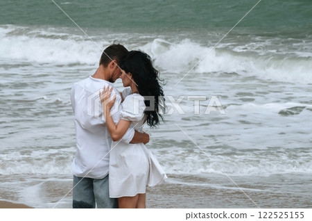 young beautiful couple in love hugging on beach by the sea in summer 122525155