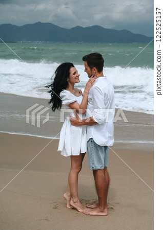 Happy young beautiful couple in love hugging on beach by the sea in summer on vacation Happy young beautiful couple in love hugging on beach by the sea in summer on vacation 122525157