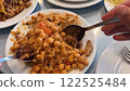 Hands Serving Meat and Rice Pilaf with Chickpeas, Carrots and Raisins on Multiple White Ceramic Plates 122525484