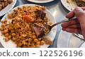 Savory Rice Pilaf with Chickpeas, Carrots, Meat, and Raisins Being Served on Multiple White Plates 122526196