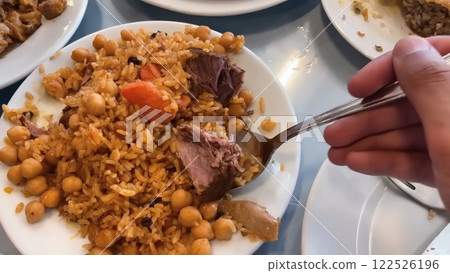 Savory Rice Pilaf with Chickpeas, Carrots, Meat, and Raisins Being Served on Multiple White Plates Savory Rice Pilaf with Chickpeas, Carrots, Meat, and Raisins Being Served on Multiple White Plates 122526196