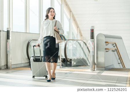 Business woman on a business trip or return trip with a suitcase riding an escalator at the station 122526201
