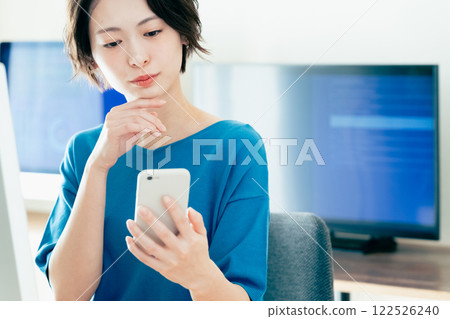 操作一個智能手機的少婦在辦公室 122526240