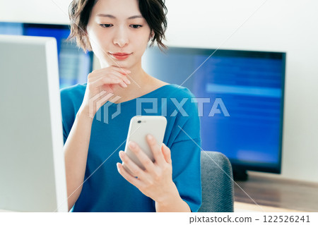 A young woman operating a smartphone in the office 122526241