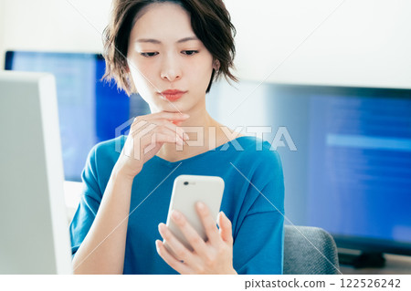 A young woman operating a smartphone in the office 122526242
