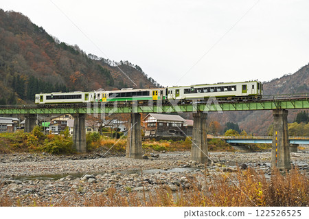 The Tadami Line running over the Kanatsugawa Bridge with autumn leaves 122526525